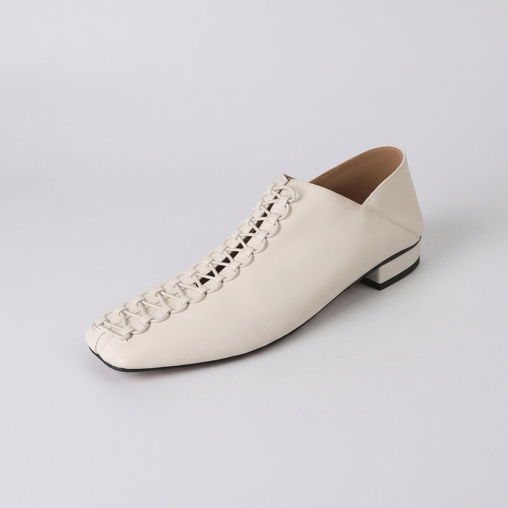 A single off-white leather shoe with a low block heel, square toe, and decorative lace-up detailing on the vamp, shown against a plain white background.