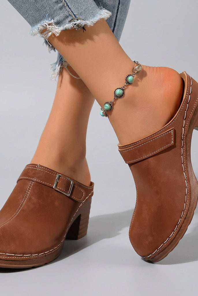 Brown clogs worn on feet with a blurred natural background
