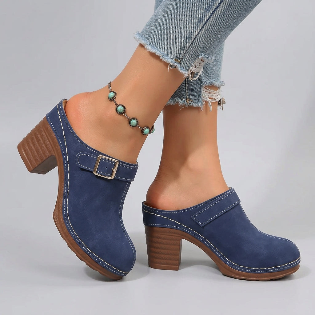 Blue clogs with brown soles worn on a sandy surface